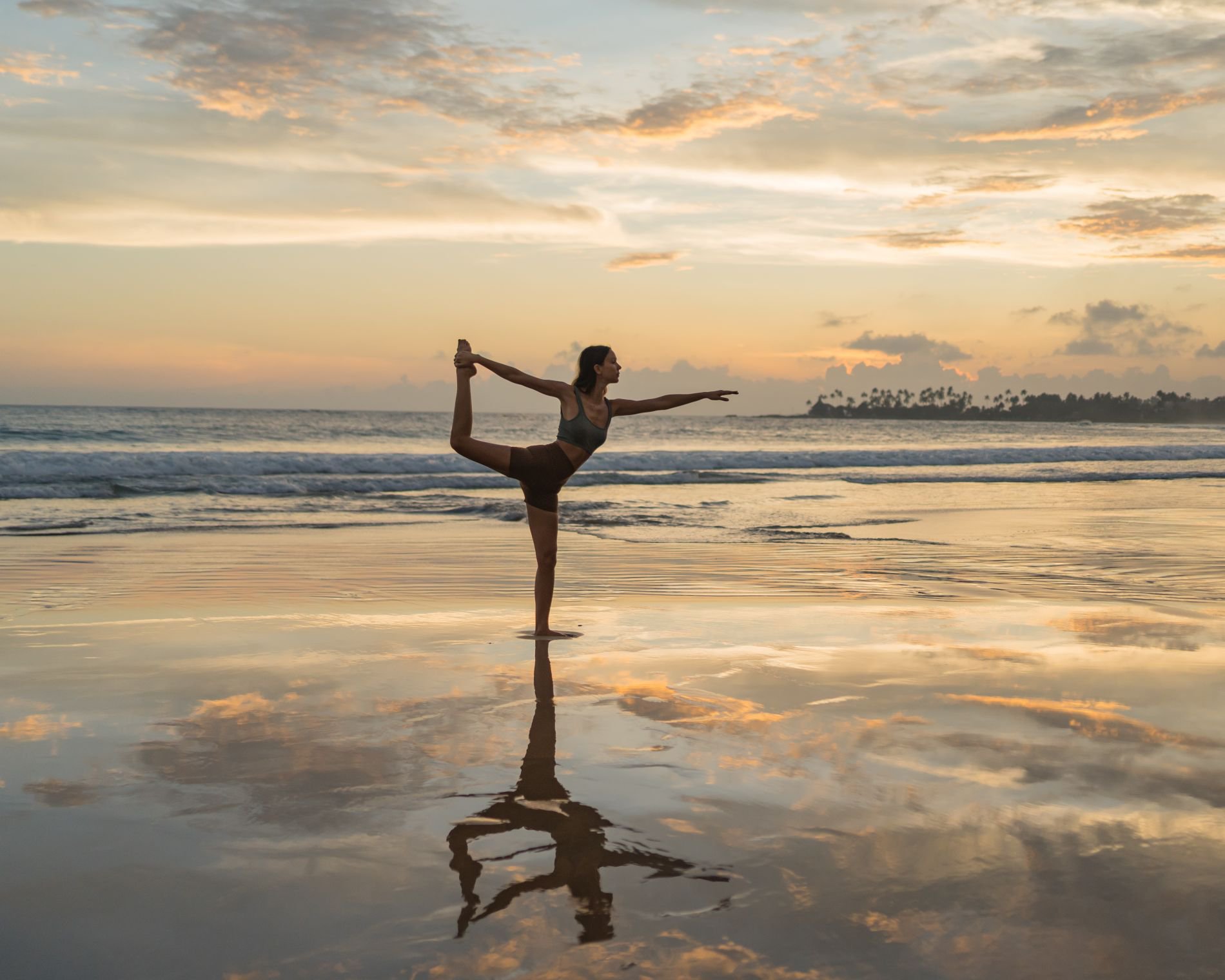 Junge Frau macht Yoga‑Übungen auf den Wattflächen im Morgenlicht | © Getty Images