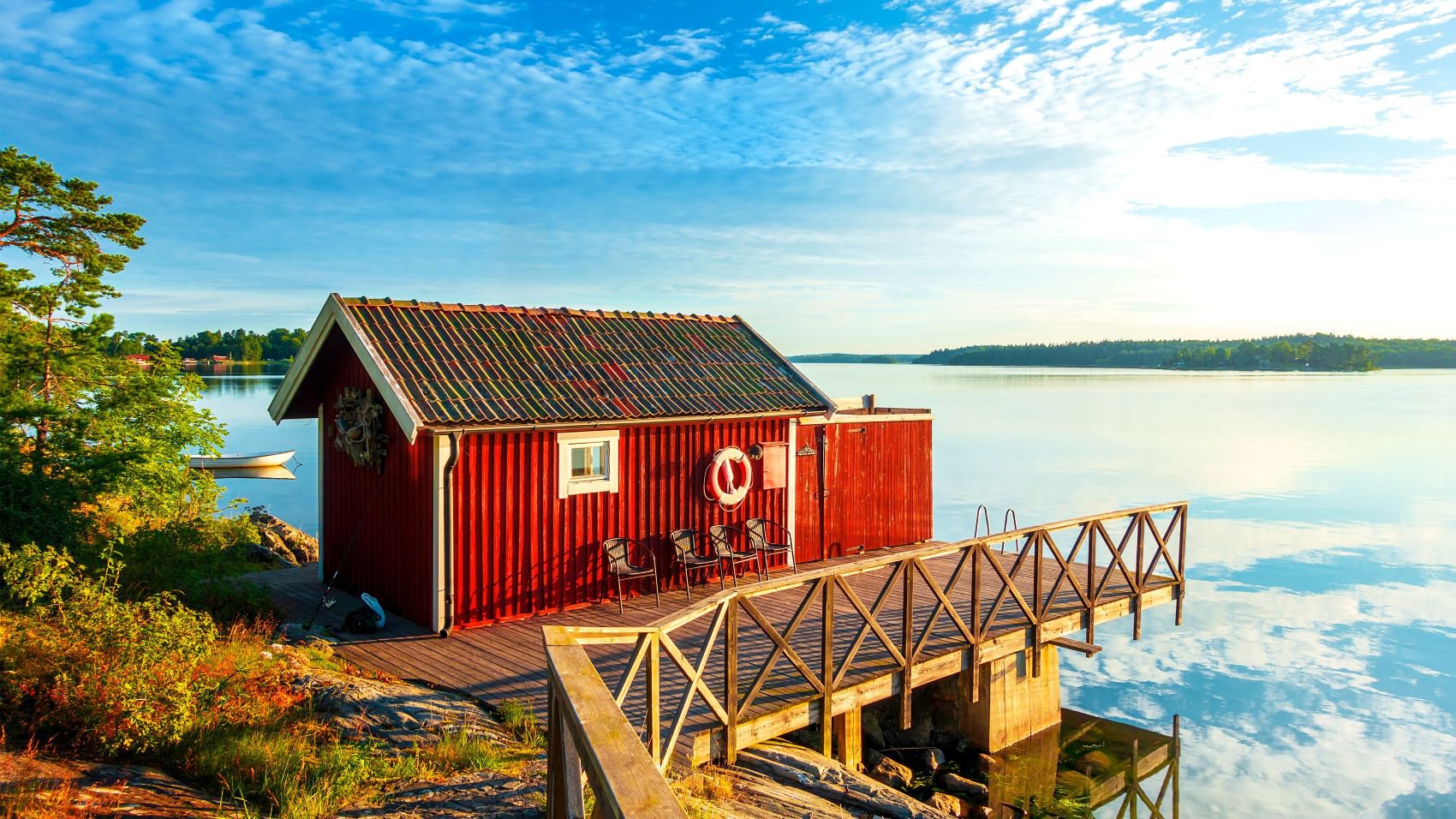 Schärenlandschaft an der Ostseeküste in Schweden mit einer roten Holzhütte, umgeben von ruhigem Wasser | © Nicko Cruises via Shutterstock