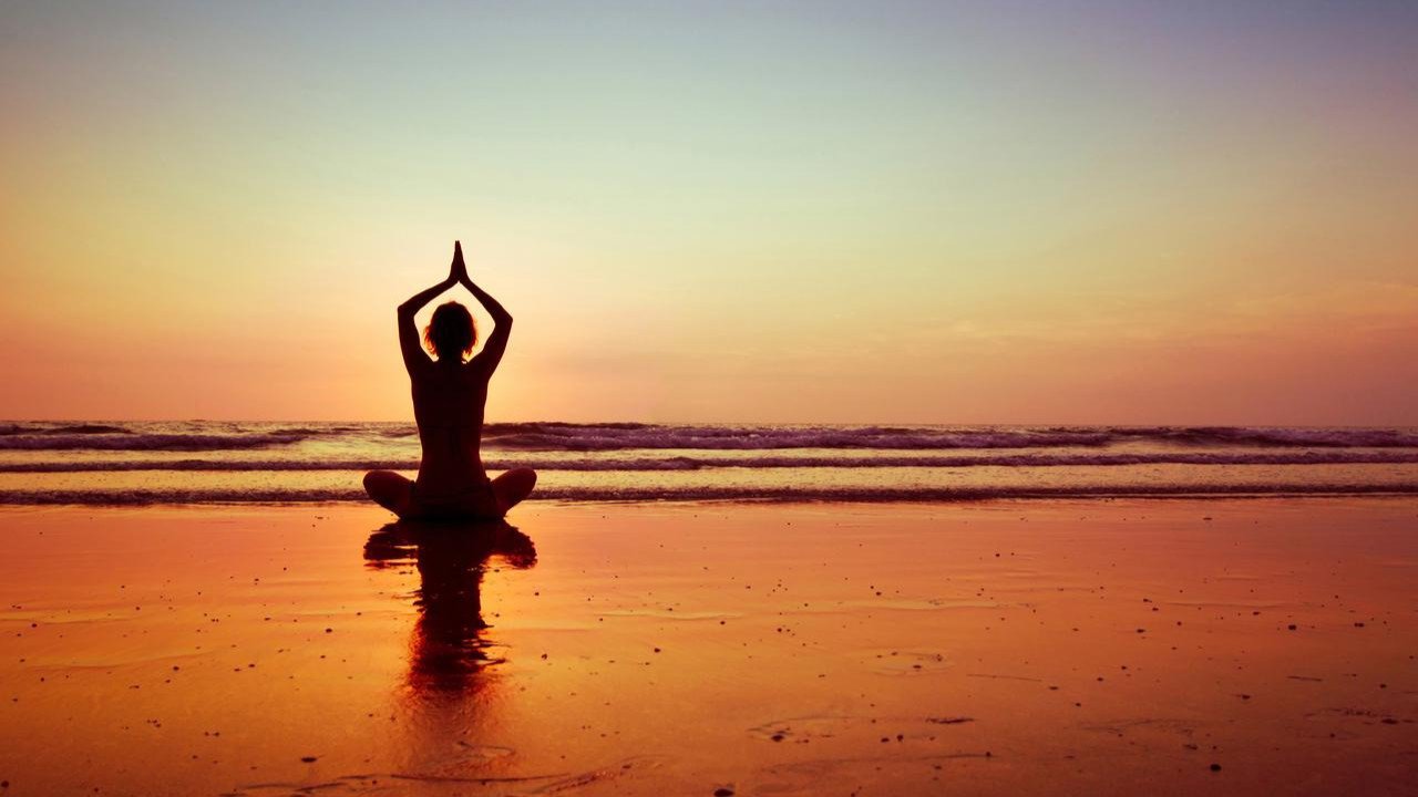 Frau am Strand auf Ibiza beim Yoga bei Sonnenaufgang | © Discover Airlines