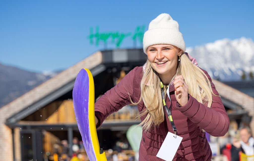 Eine Frau nimmt an einem Wettbewerb teil, im Hintergrund ist eine Alm zu sehen.
