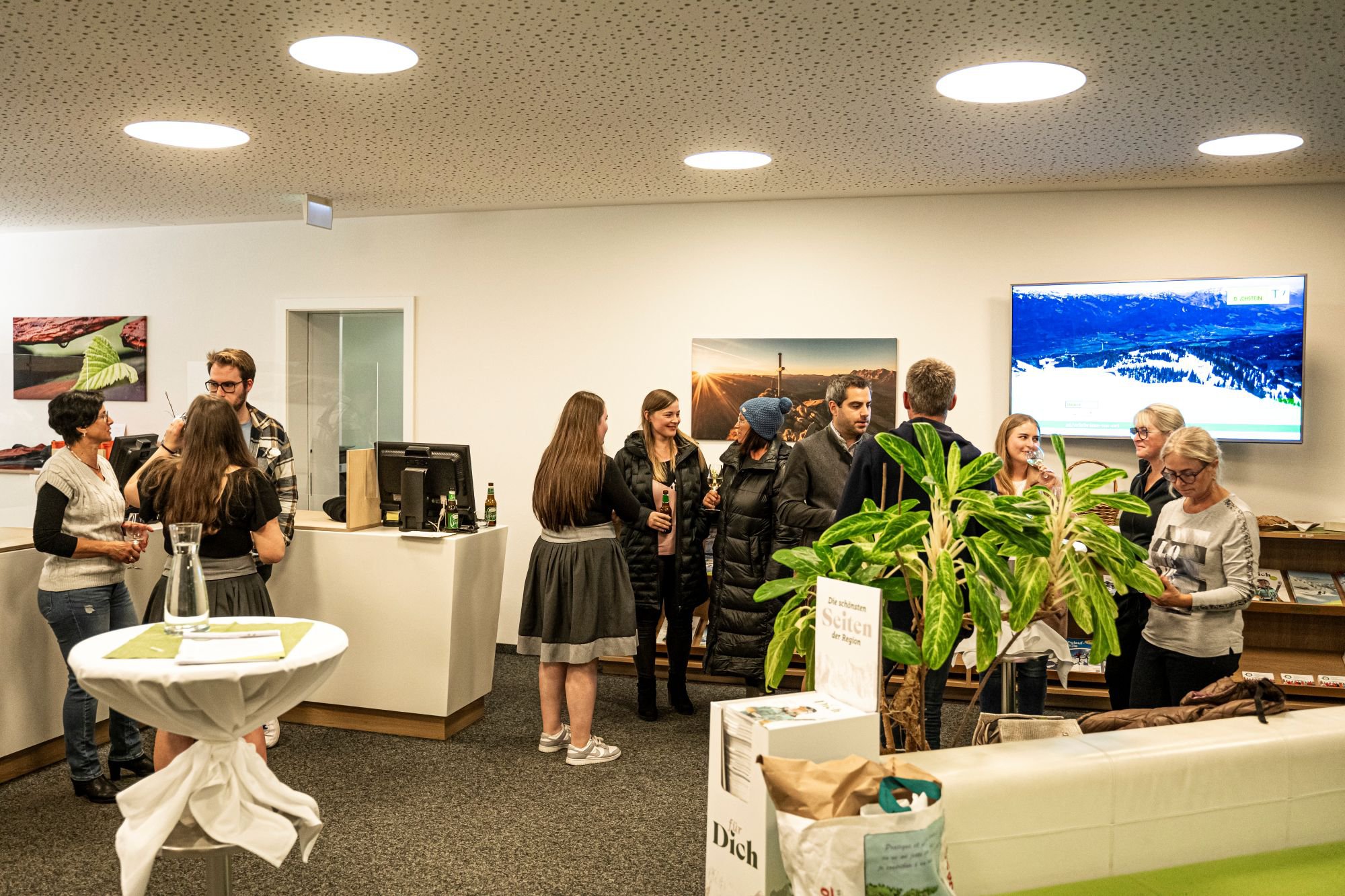 In einem hellen Raum stehen viele Personen in kleinen Gruppen beieinander und unterhalten sich.