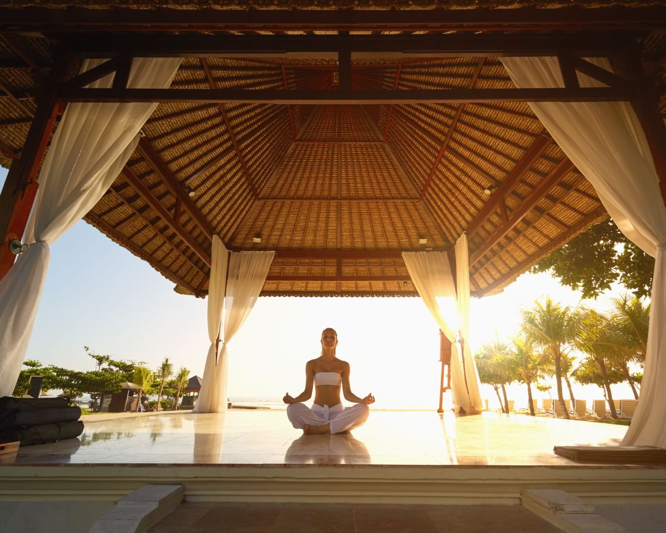 Frau meditiert in einem Pavillon am Strand | © Getty Images