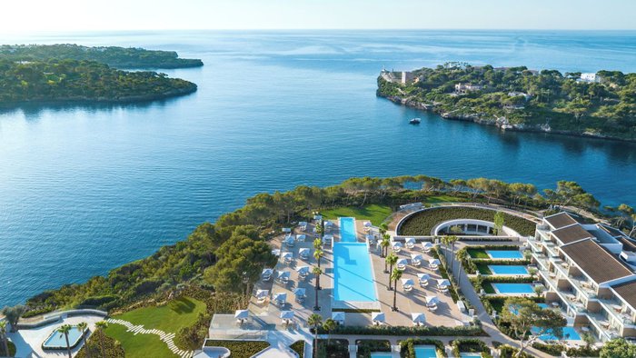 Panoramablick auf das Ikos Porto Petro auf Mallorca mit modernen Hotelgebäuden, mehreren Pools und direkter Lage an einer türkisblauen Bucht des Mittelmeers | © Ikos Resorts