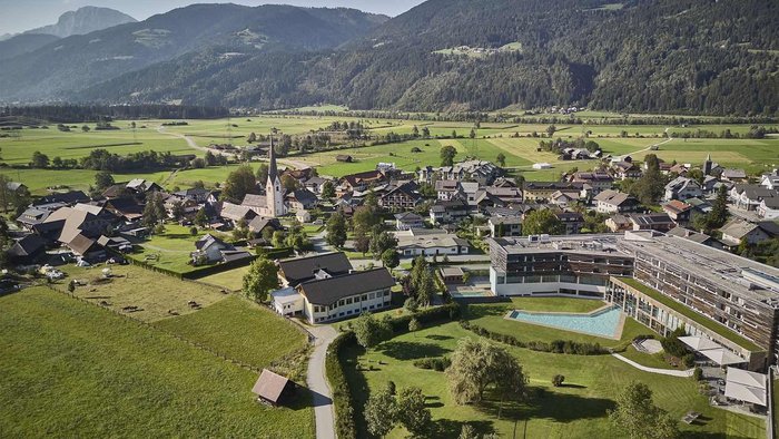 Drohnenaufnahme des Falkensteiner Hotel & Spa Carinzia inmitten der Kärntner Berglandschaft mit moderner Architektur und großzügiger Hotelanlage | © Falkensteiner Hotel & Spa Carinzia
