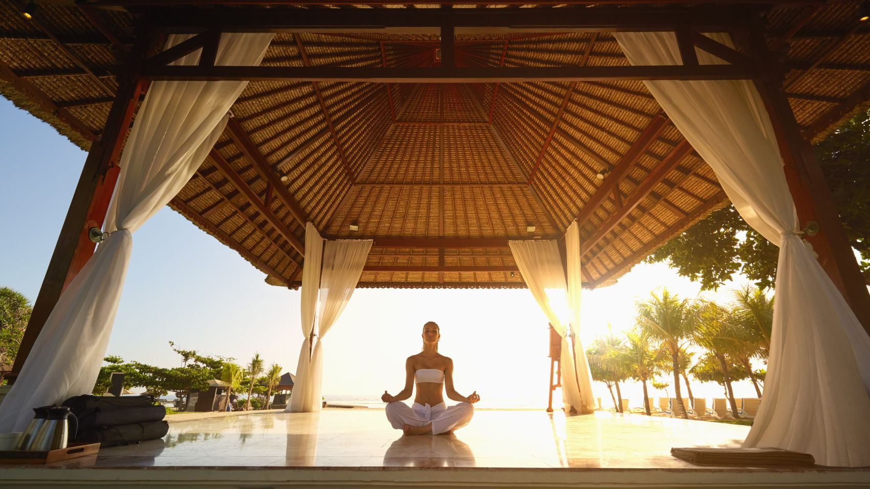 Eine Frau, die in einem offenen Strandpavillon meditiert | © Getty Images