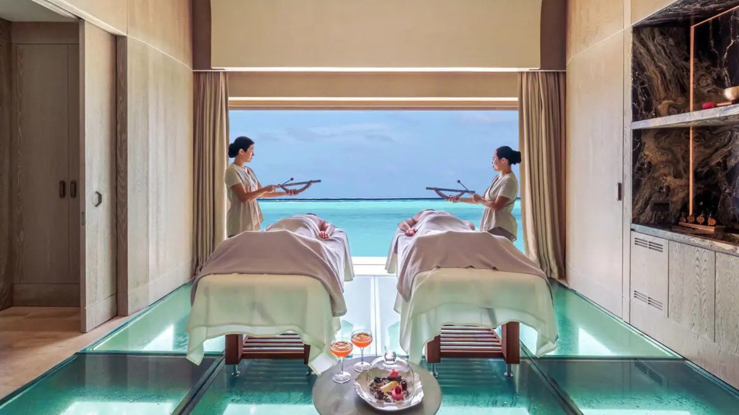 Zwei Gäste liegen entspannt auf Liegen mit Blick auf das türkisblau schimmernde Meer und genießen die ruhige Atmosphäre der Insel | © Joali Being