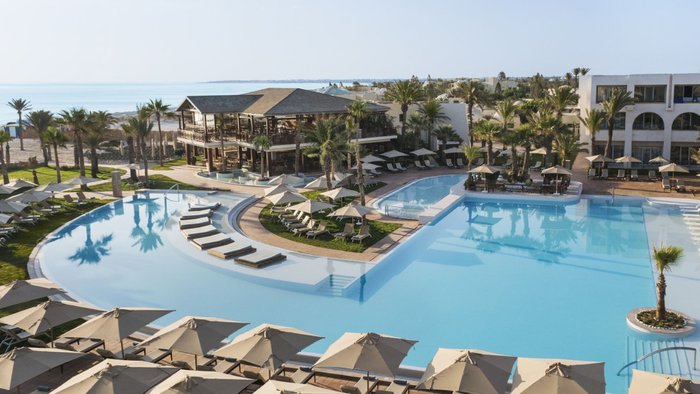 Poolbereich mit Liegen vor der Hotelanlage des Iberostar Selection Eolia Djerba, im Hintergrund Strand und Meer | © Iberostar Hotel Group