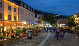 uf dem Hauptplatz in Schladming sind bei einsetzender Dämmerung zahlreiche Menschen unterwegs.