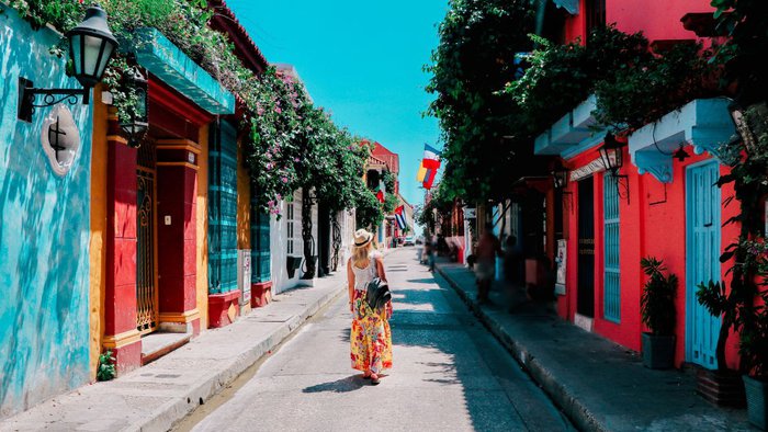 Junge Frau geht auf einer bunten Straße in der Altstadt von Cartagena, Kolumbien | © Getty Images