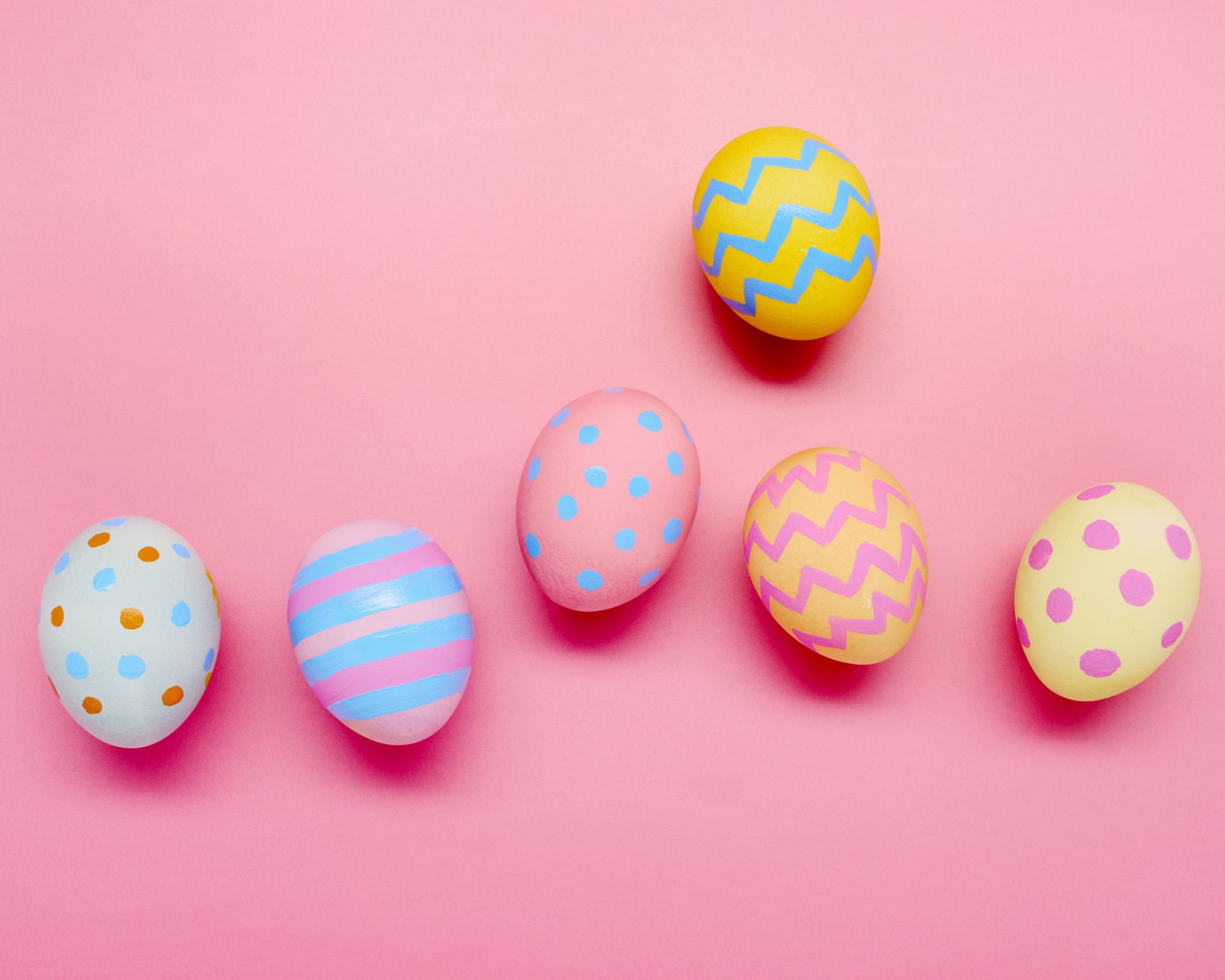 Auf einem rosa Hintergrund liegen mehrere bunte, bemalte Ostereier | © Getty Images