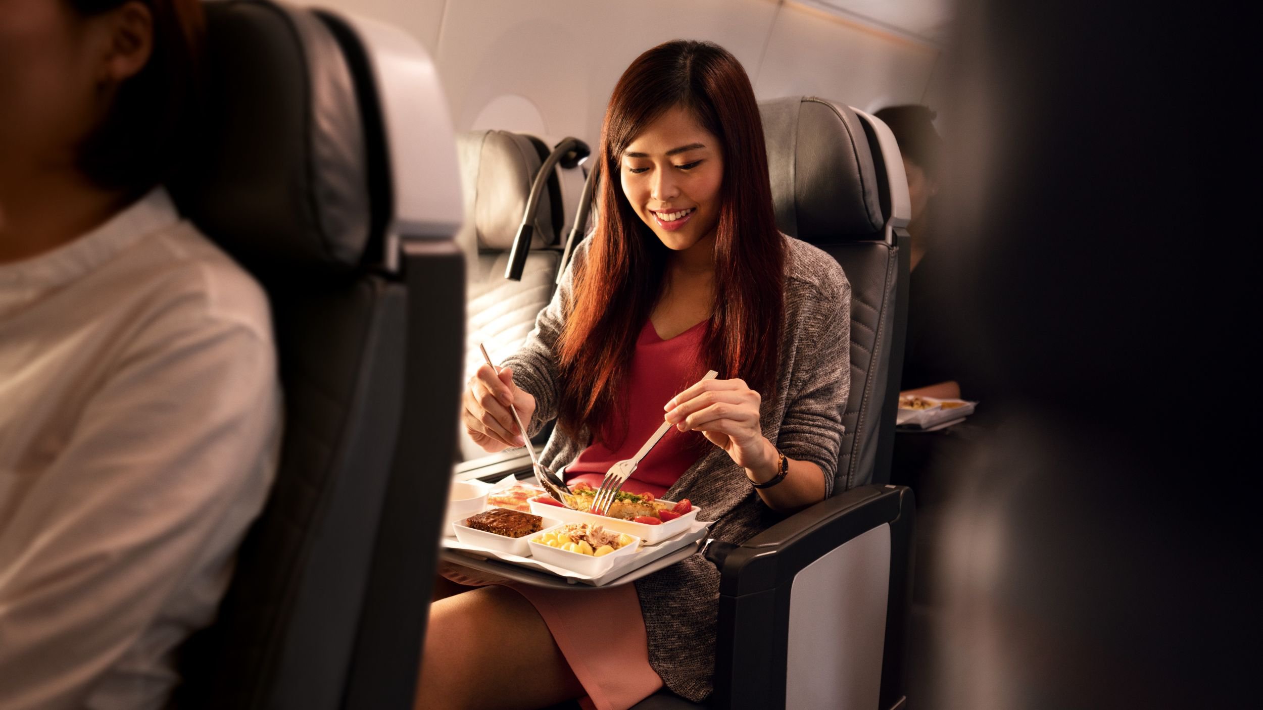 Passagierin genießt eine Mahlzeit an Bord eines Singapore Airlines Fluges | © Singapore Airlines