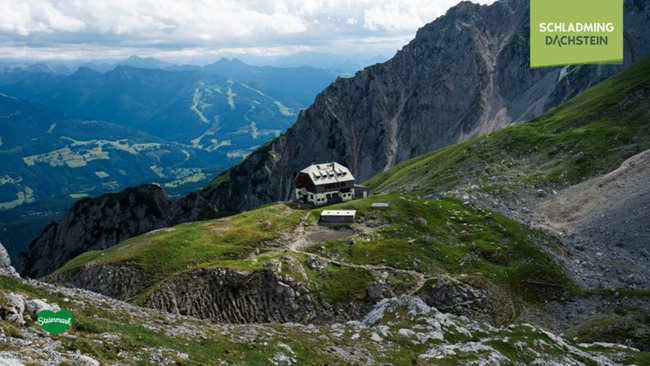 Inmitten einer rauen, felsigen Berglandschaft thront das Guttenberghaus auf einem Hochplateau und bietet einen beeindruckenden Ausblick auf die umliegenden Gipfel.