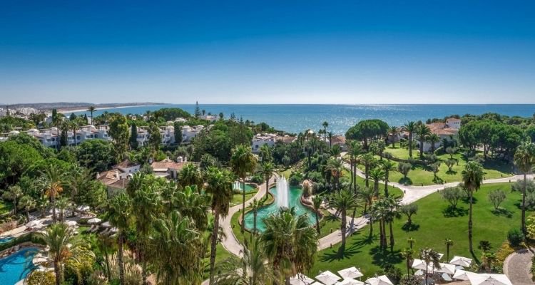 Hotelgelände des Vila Vita Parc mit einladenden Pools, grünen Gärten und Blick auf das glitzernde Meer im Hintergrund | © Vila Vita Parc